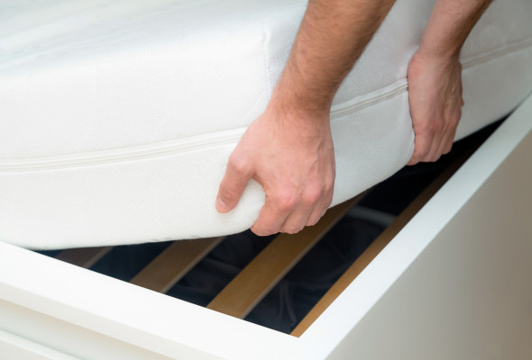 man-hands-lifting-the-mattress-at-the-bedroom-looking-at-the-bed-frame.jpg