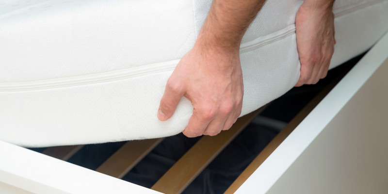 man-hands-lifting-the-mattress-at-the-bedroom-looking-at-the-bed-frame.jpg